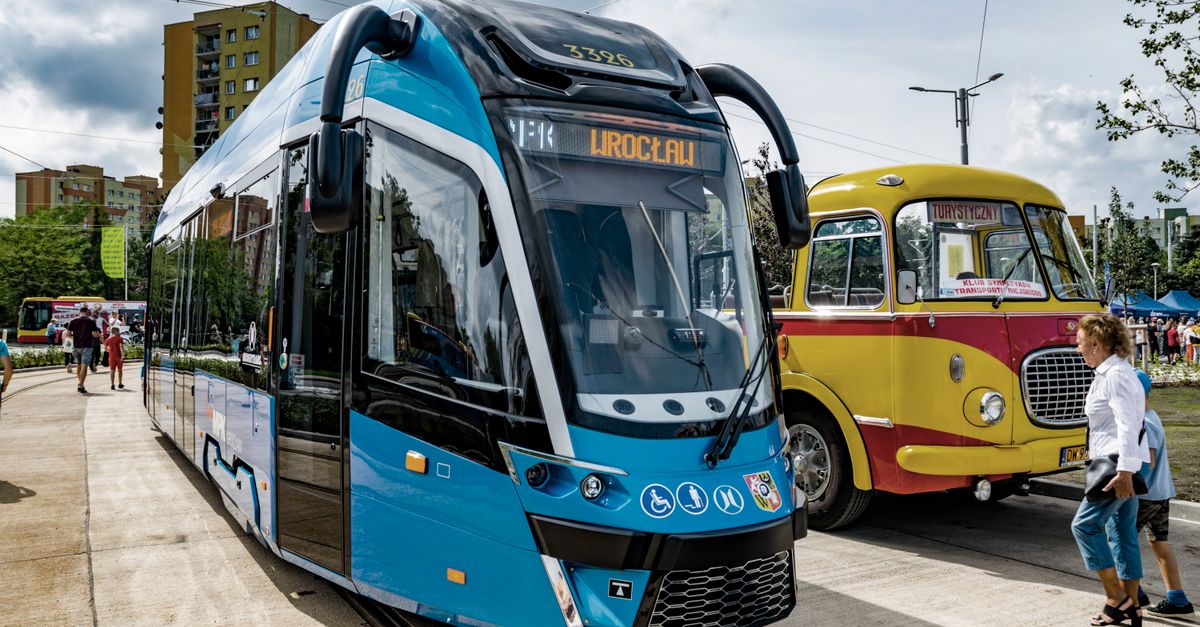 A modern tram alongside a vintage bus in Wrocław, showcasing contrast in public transportation.